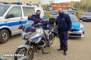 policjantka i policjant stoją obok chłopca siedzącego na motocyklu