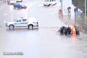 policjanci pchają samochód na zalanej ulicy