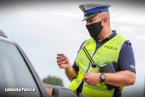 policjant kontroluje dokument kierowcy