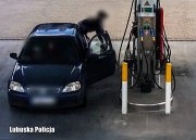 Pojazd na stacji benzynowej, a obok mężczyzna tankujący paliwo.