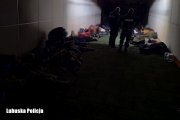 policjanci oraz leżące i siedzące osoby w ciemnym pomieszczeniu