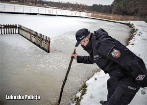 Policjant sprawdza grubość lodu nad jeziorem.
