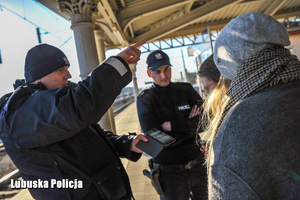 policjanci pomagający osobom odnaleźć właściwy peron