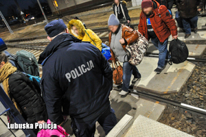 policjant obserwuje osoby idące peronem