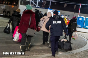 Policjant pomaga przenieść bagaże przyjezdnym z Ukrainy
