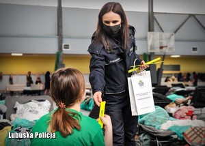 Policjantka wręcza dziewczynce opaskę odblaskową