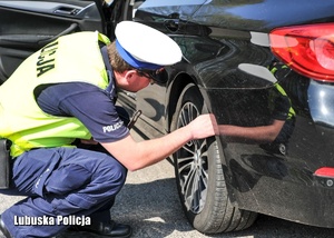 Policjant sprawdza stan techniczny pojazdu oraz ogumienia