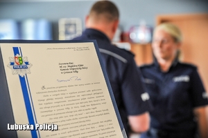 list gratulacyjny i w tle policjant gratulujący policjantce