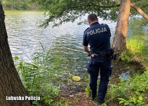Policjant stojący nad brzegiem jeziora.