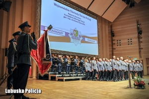 Na scenie policjanci z pocztu sztandarowego, wyróżnieni policjanci oraz policyjna orkiestra
