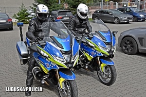 Policjanci na motocyklach stojący na parkingu.