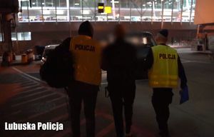 Nieumundurowani policjanci podczas konwoju zatrzymanego mężczyzny na lotnisku.