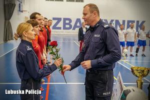 Komendant Wojewódzki Policji wręcza róże policjantce na turnieju piłki nożnej.