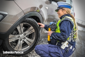 policjantka kontroluje stan ogumienia pojazdu