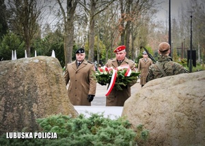 Żołnierze składają kwiaty przed pomnikiem.