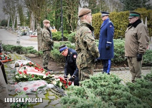 Przedstawiciele służb mundurowych składają kwiaty przed pomnikiem.