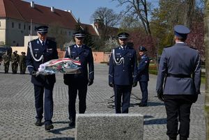 Policjanci składają wiązankę kwiatów przed pomnikiem.