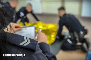 policjanci prowadzą pierwszą pomoc medyczną na manekinie