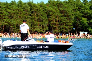 Policjanci sprawdzają bezpieczeństwo kąpiącym się w jeziorze osobom.