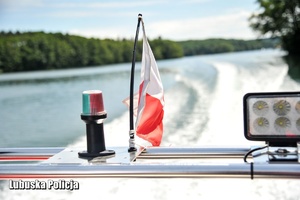 Flaga Polski na łodzi motorowej, a w tle jezioro.
