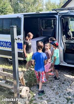 Dzieci stojące przy policyjnym radiowozie.