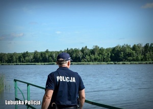Policjant, a w tle jezioro.