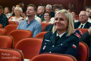Policjantka i inne osobowy siedzące na widowni w teatrze.