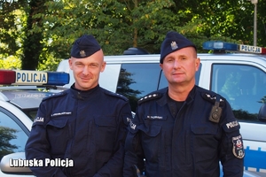 Policjanci stojący przy radiowozie policyjnym.