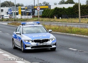 Policyjny radiowóz jadący drogą.