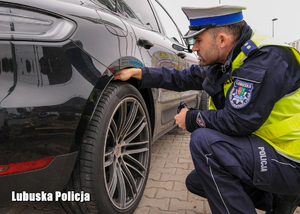 Policjant drogówki sprawdza ogumienie w pojeździe.