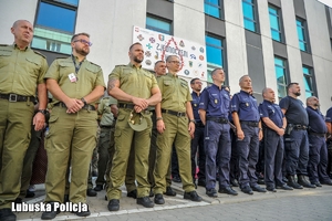 Funkcjonariusze Służby Celno-Skarbowej  oraz policjanci stojący w szeregu.