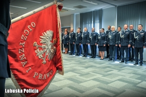 poczet sztandarowy i policjanci w tle