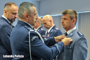 Komendant wręcza odznaczenie policjantowi.