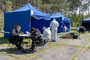 Policjanci sporządzają dokumentację konkursową na tle niebieskich namiotów.