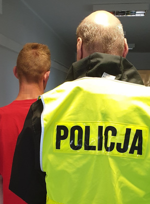 Policjant prowadzi zatrzymanego mężczyznę