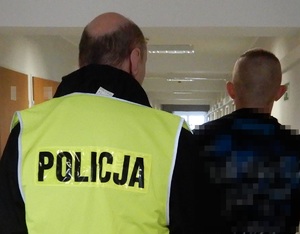 Policjant prowadzi zatrzymanego mężczyznę