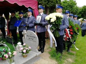 policjanci stoją nad grobem z kwiatami i zdjęciem zmarłego