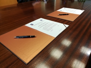 Dwa egzemplarze porozumienia leżą na stole, a na nich długopisy