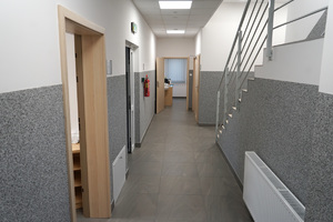 zdjęcie holu, na którym znajdują się drzwi do pokoi oraz schody z poręczami prowadzące na pierwsze piętro