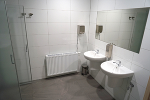 widok na dwie umywalki oraz duże lustro zawieszone na ścianie