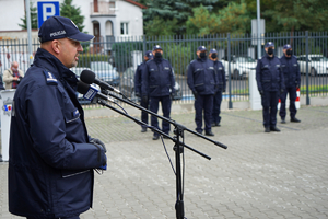 Komendant Wojewódzki Policji w Bydgoszczy przemawia do mikrofonu. W tle stoją policjanci ustawieni w szeregu
