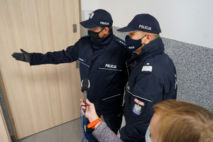 Kierownik posterunku oprowadza Pierwszego Zastępcę Komendanta Głównego Policji po budynku. Pokazuje pokoje