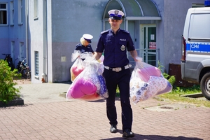 Policjanci niosą maskotki zapakowane w torby foliowe