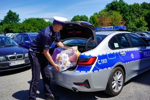 Policjant wkłada maskotki do bagażnika radiowozu