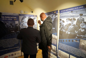 Prezydent Torunia oraz policjant oglądają wystawę znajdującą się w jednej z sal wewnątrz budynku.