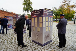 Prezydent Torunia oraz policjant czytają informacje na panelach wystawy.