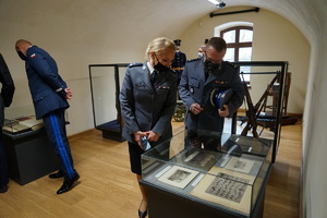 Policjanci oglądają eksponaty wystawy  znajdujące się w gablocie.