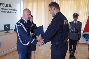 komendant wojewódzki gratuluje i wręcza rozkaz personalny policjantowi