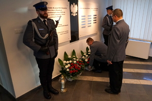 przed Tablicą Pamięci stoi jeden policjant, drugi składa kwiaty