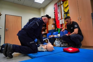 Policjant przeprowadza resuscytację na manekinie leżącym na ziemi
